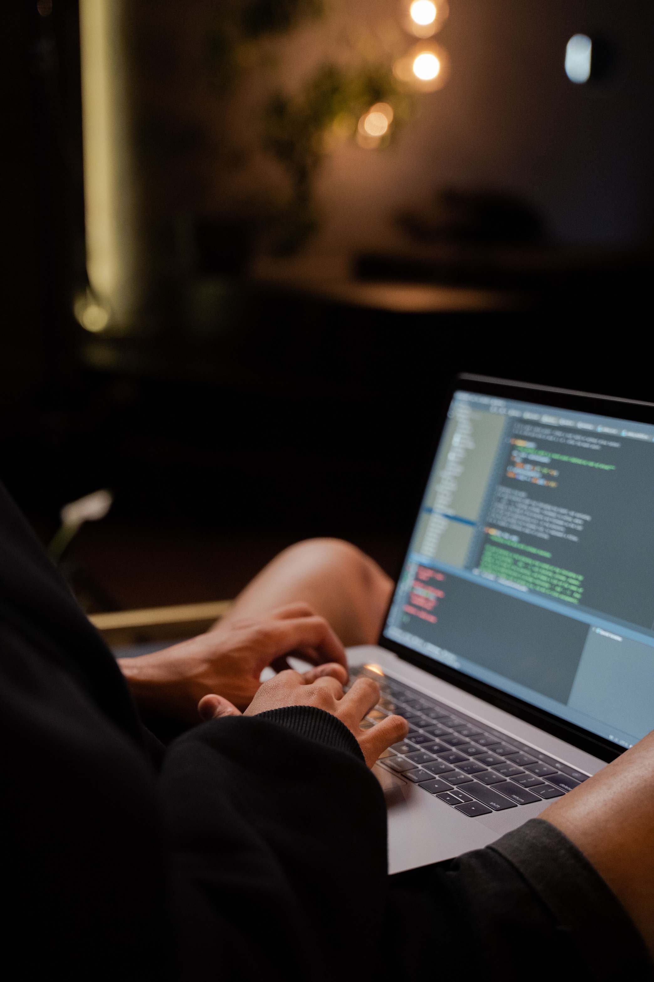 Hände an Tastatur vor Code-Editor auf dem Bildschirm